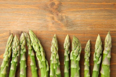 Fresh green asparagus stems on wooden table, top view. Space for text