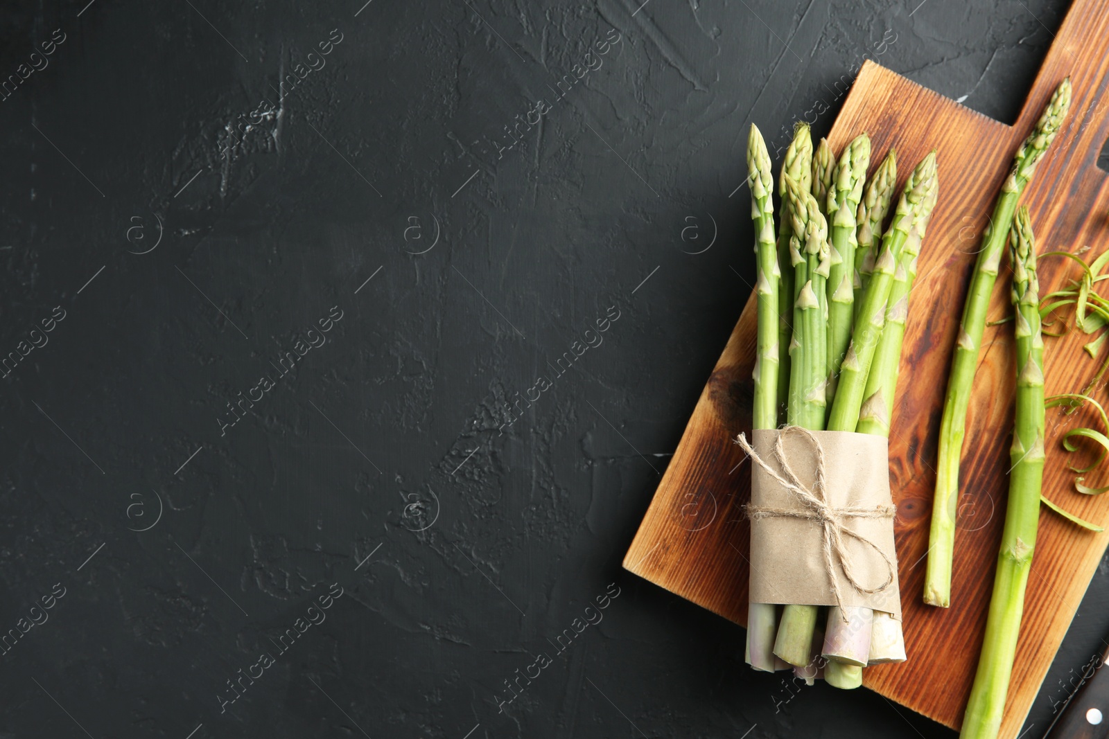 Photo of Fresh green asparagus stems on gray textured table, flat lay. Space for text