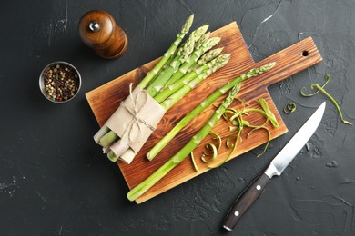 Photo of Fresh green asparagus stems, spices and knife on gray textured table, flat lay