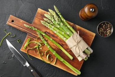 Photo of Fresh green asparagus stems, spices and knife on gray textured table, flat lay