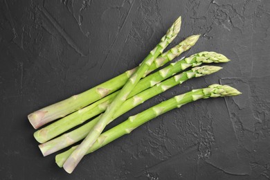 Photo of Fresh green asparagus stems on gray textured table, top view