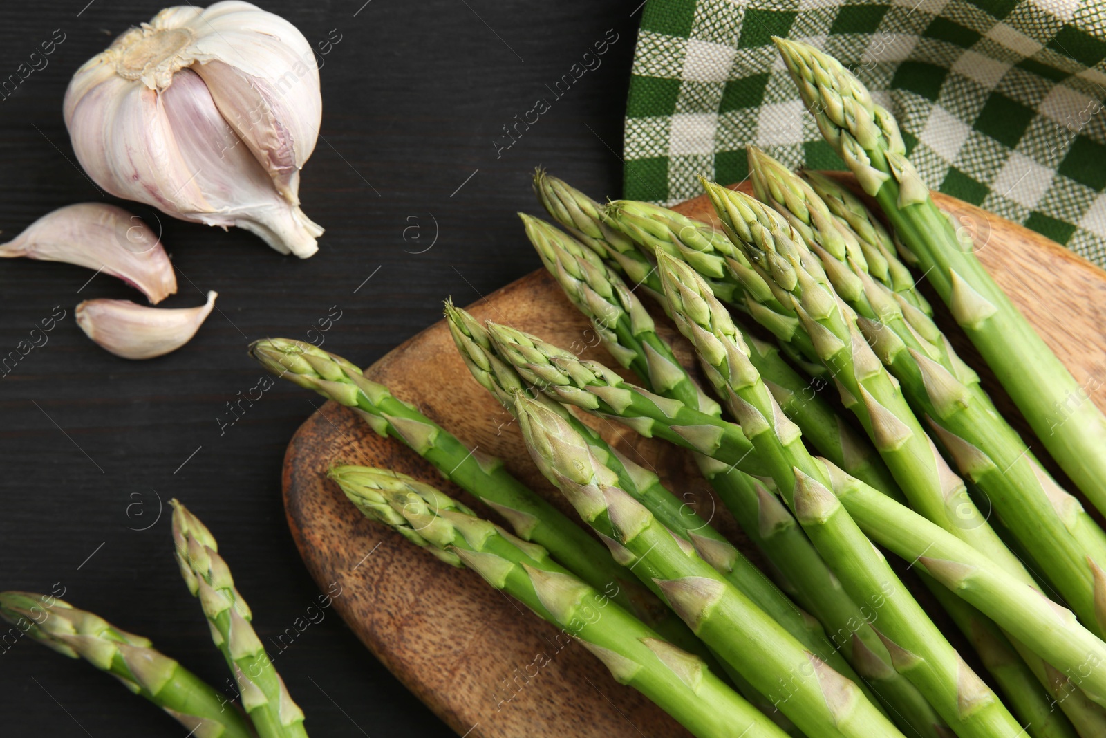 Photo of Fresh green asparagus stems and garlic on gray wooden table, flat lay