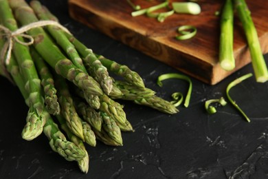 Fresh green asparagus stems on black textured table, closeup