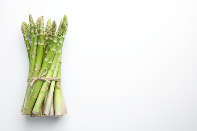 Bunch of fresh green asparagus stems on white table, top view. Space for text