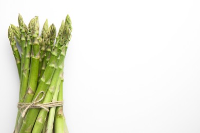 Photo of Bunch of fresh green asparagus stems on white table, top view. Space for text