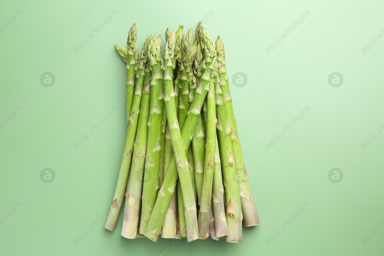 Photo of Fresh asparagus stems on green table, top view