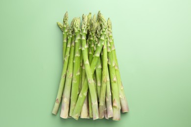 Photo of Fresh asparagus stems on green table, top view