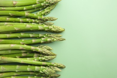 Photo of Fresh asparagus stems on green table, top view. Space for text