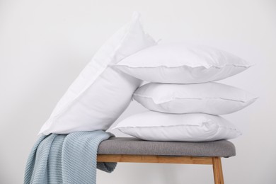 Clean pillows, blanket and storage bench near white wall