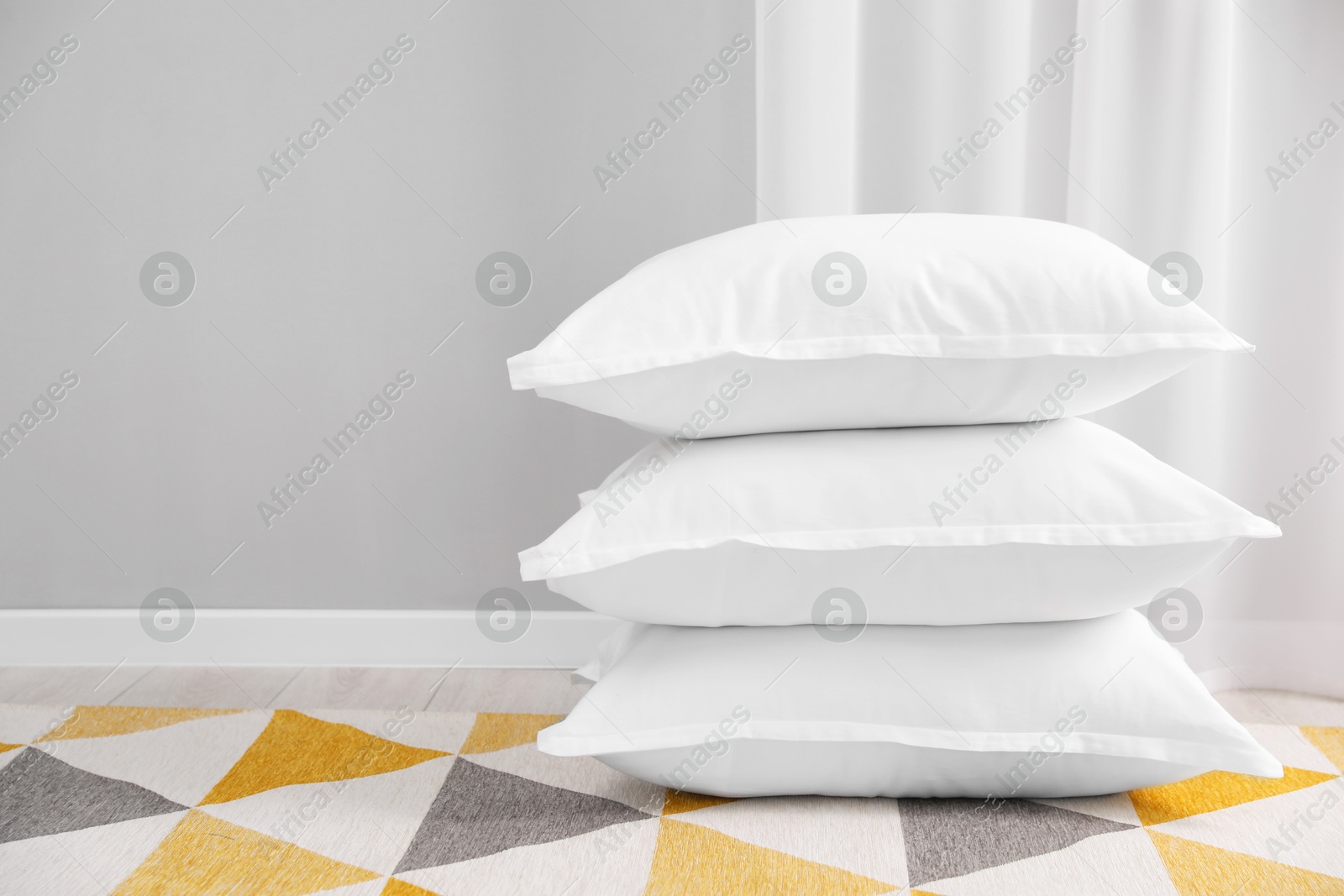 Photo of Stack of white pillows on floor indoors. Space for text