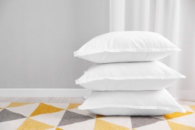 Photo of Stack of white pillows on floor indoors. Space for text