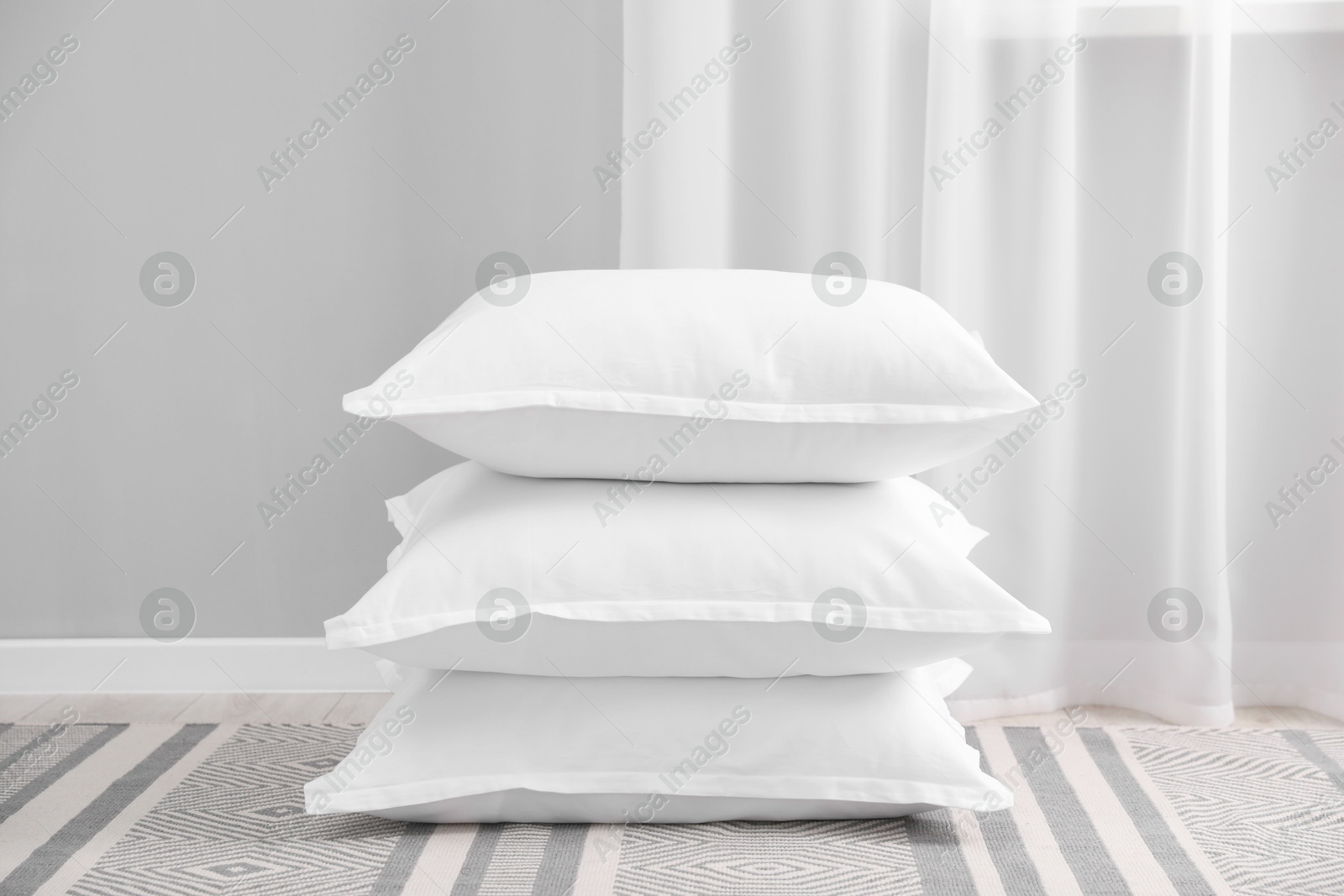 Photo of Stack of white pillows on floor indoors