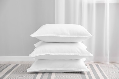 Stack of white pillows on floor indoors