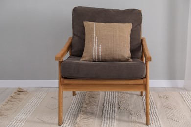 Photo of Soft armchair with pillow on carpet indoors