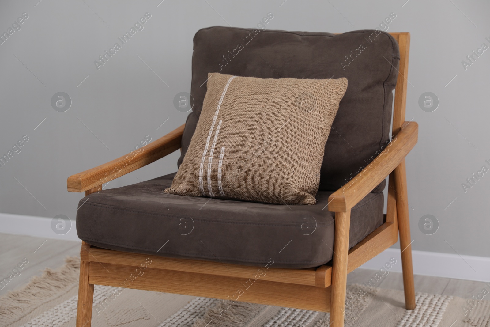 Photo of Soft armchair with pillow on carpet indoors