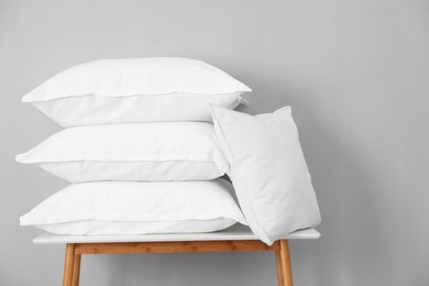 Photo of Stack of pillows on bench against grey wall