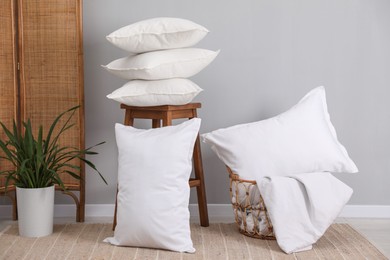 Stack of pillows, stool, storage basket and houseplant on floor indoors