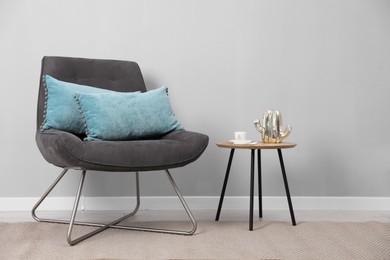 Photo of Soft pillows on armchair near coffee table indoors