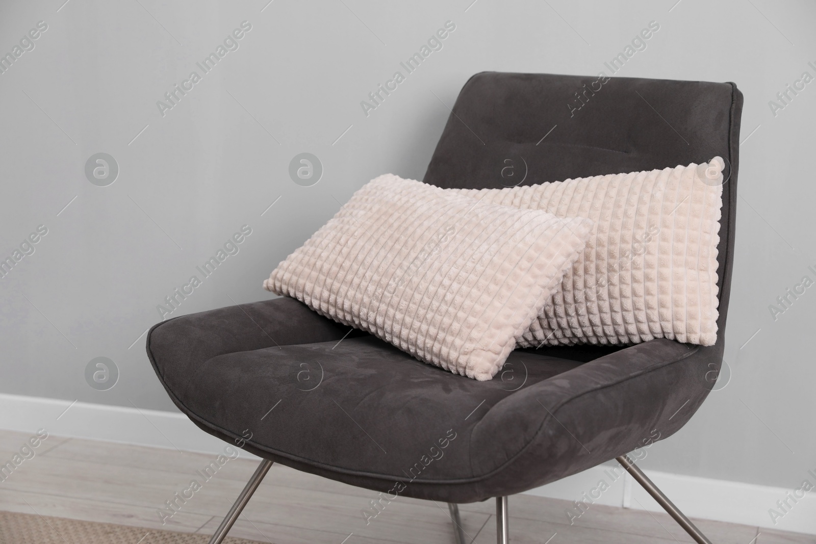 Photo of Soft armchair with pillows on floor indoors