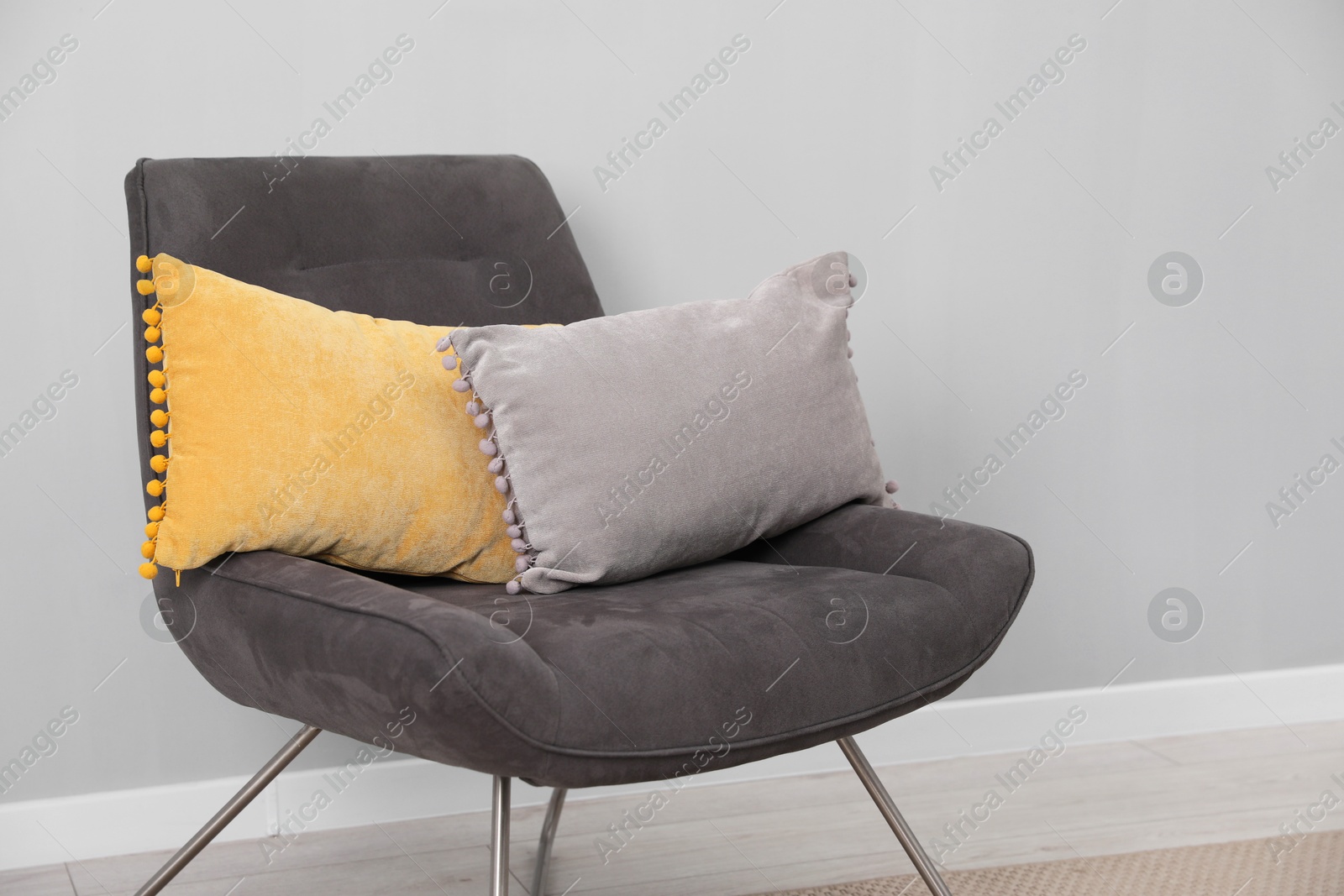 Photo of Soft armchair with pillows on floor indoors