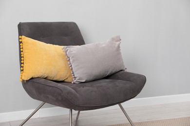 Photo of Soft armchair with pillows on floor indoors