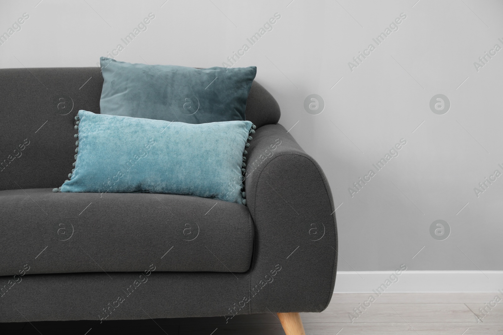 Photo of Soft sofa with pillows on floor indoors. Space for text