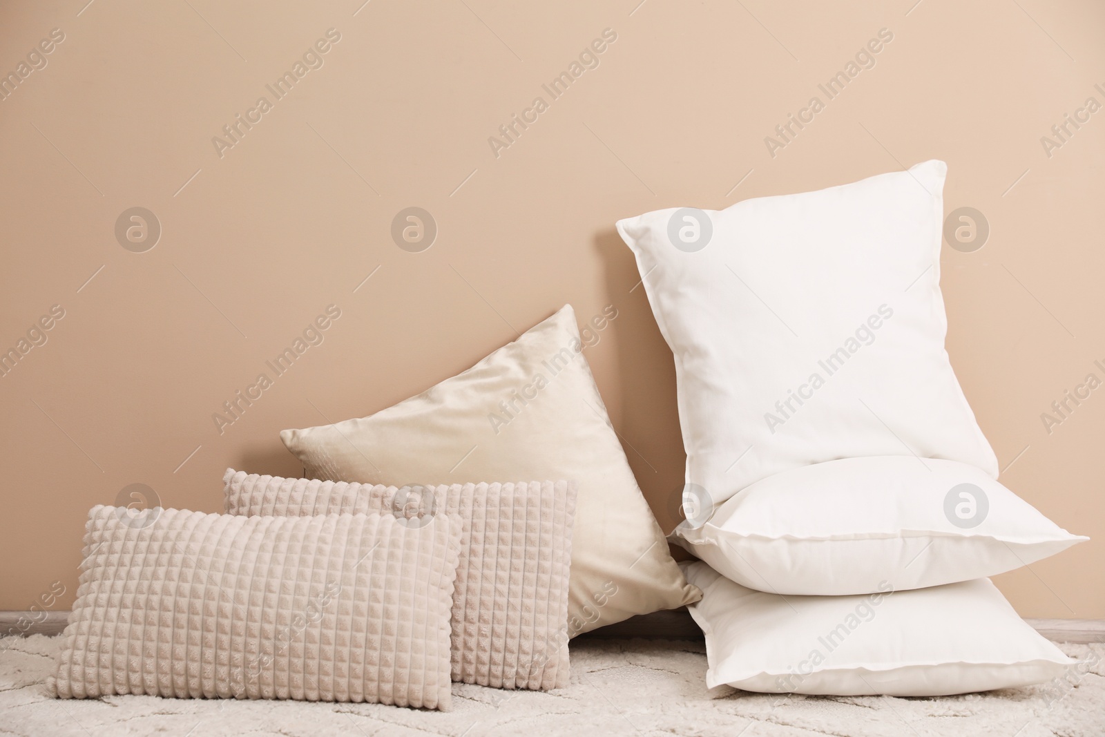 Photo of Soft pillows on floor near beige wall