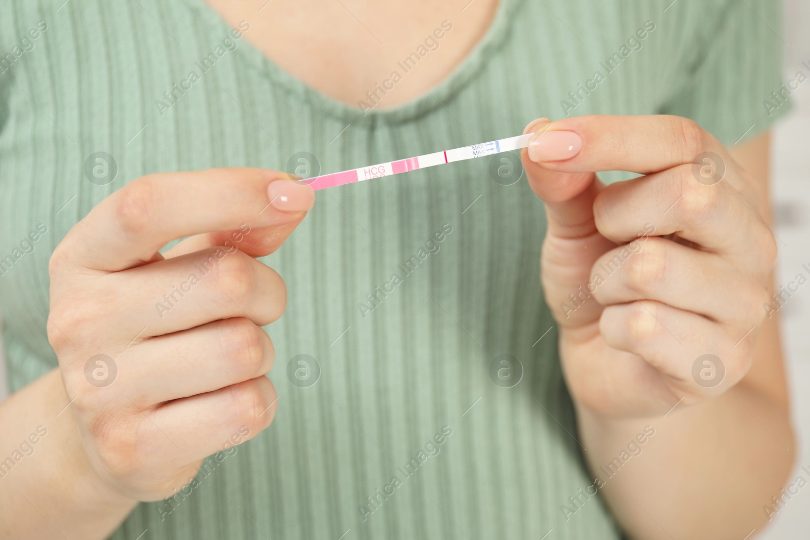 Photo of Woman holding negative pregnancy test indoors, closeup view