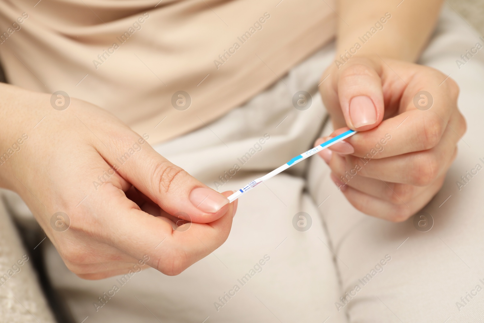 Photo of Woman holding pregnancy test indoors, closeup view