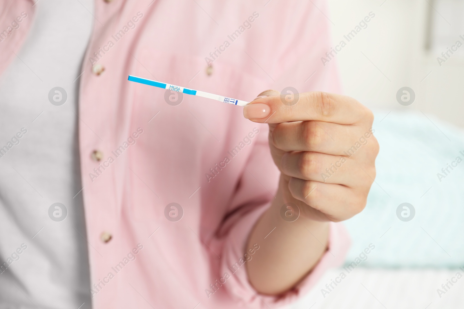 Photo of Woman holding pregnancy test indoors, closeup view