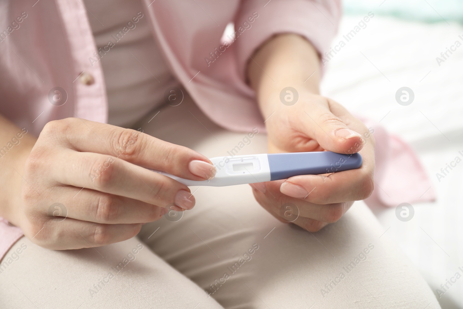 Photo of Woman holding pregnancy test indoors, closeup view