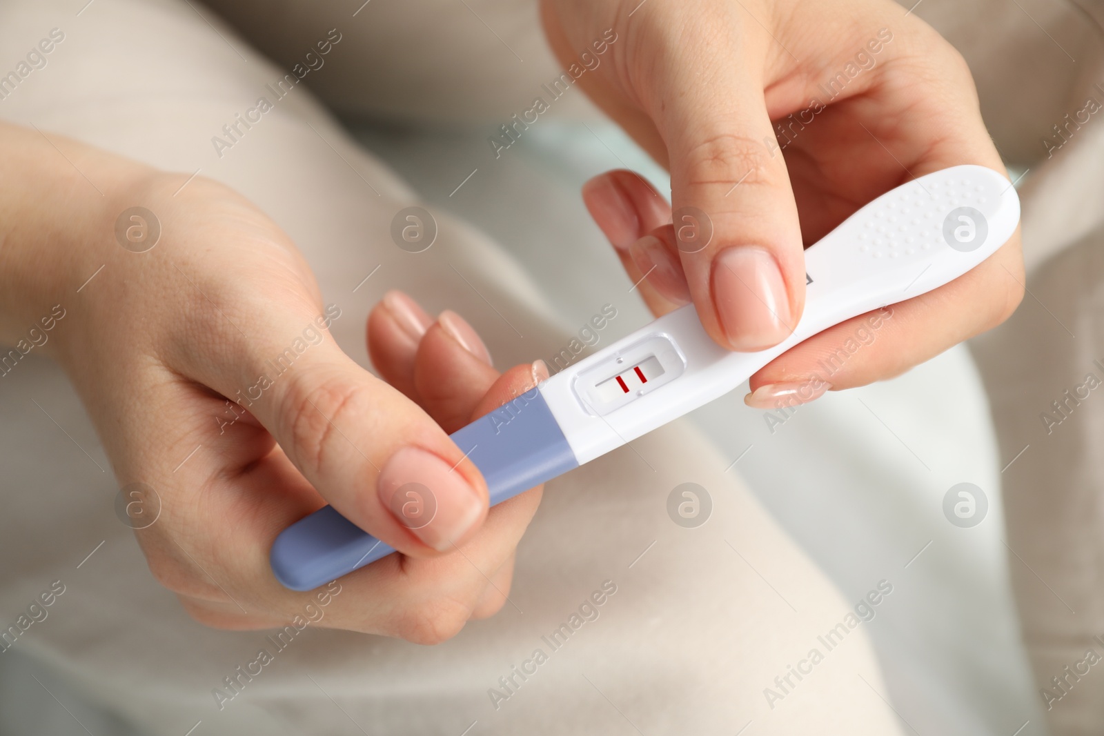 Photo of Woman holding positive pregnancy test indoors, closeup view