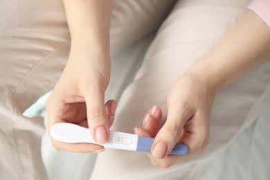 Woman holding negative pregnancy test indoors, closeup view