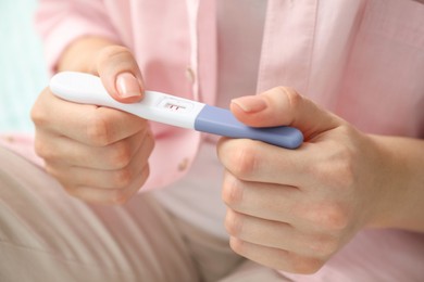 Woman holding negative pregnancy test indoors, closeup view