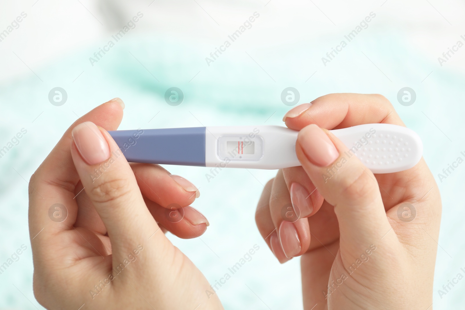 Photo of Woman holding positive pregnancy test indoors, closeup view