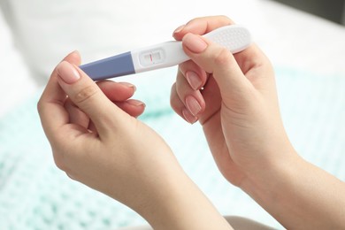 Photo of Woman holding negative pregnancy test indoors, closeup view