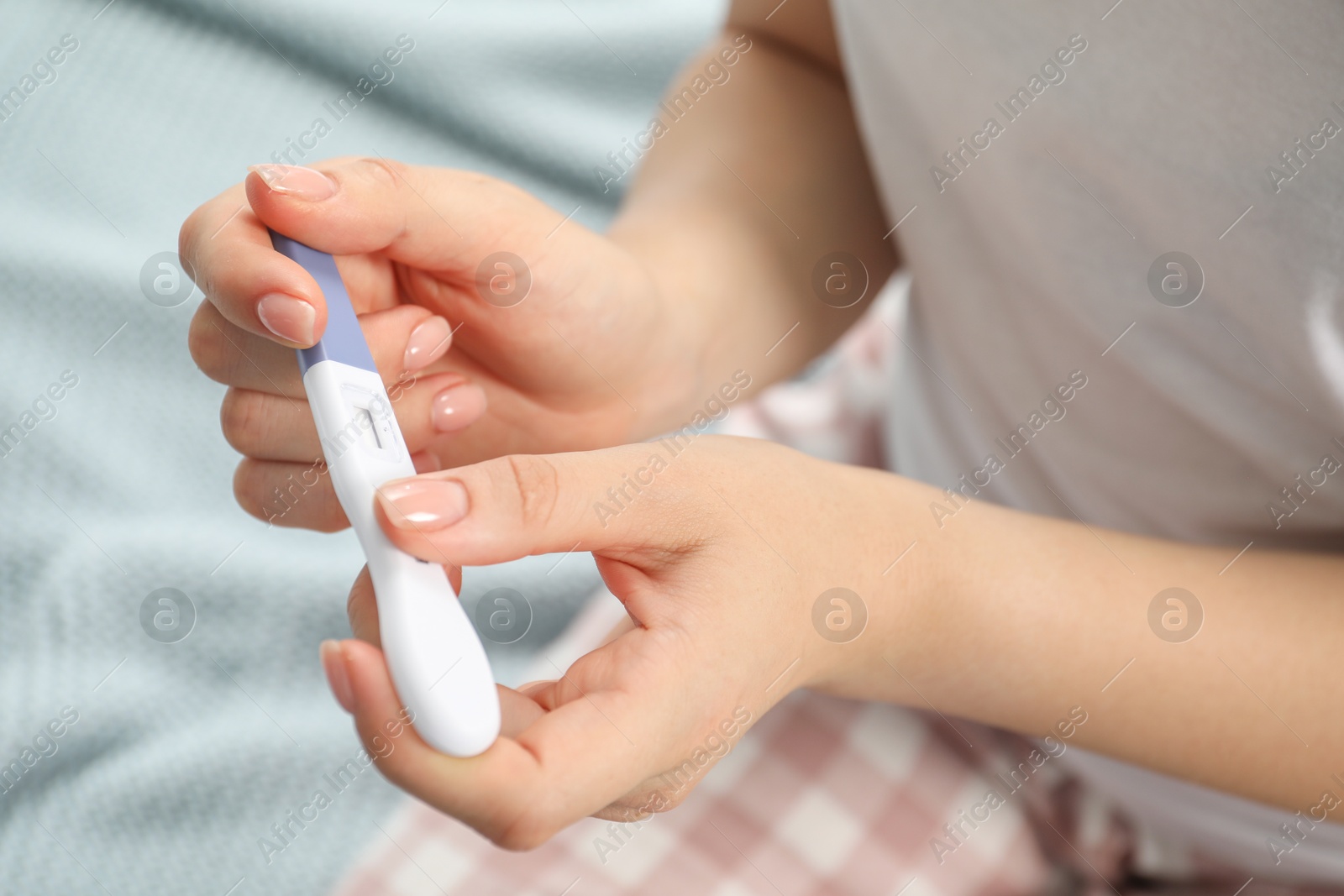 Photo of Woman holding pregnancy test indoors, closeup view