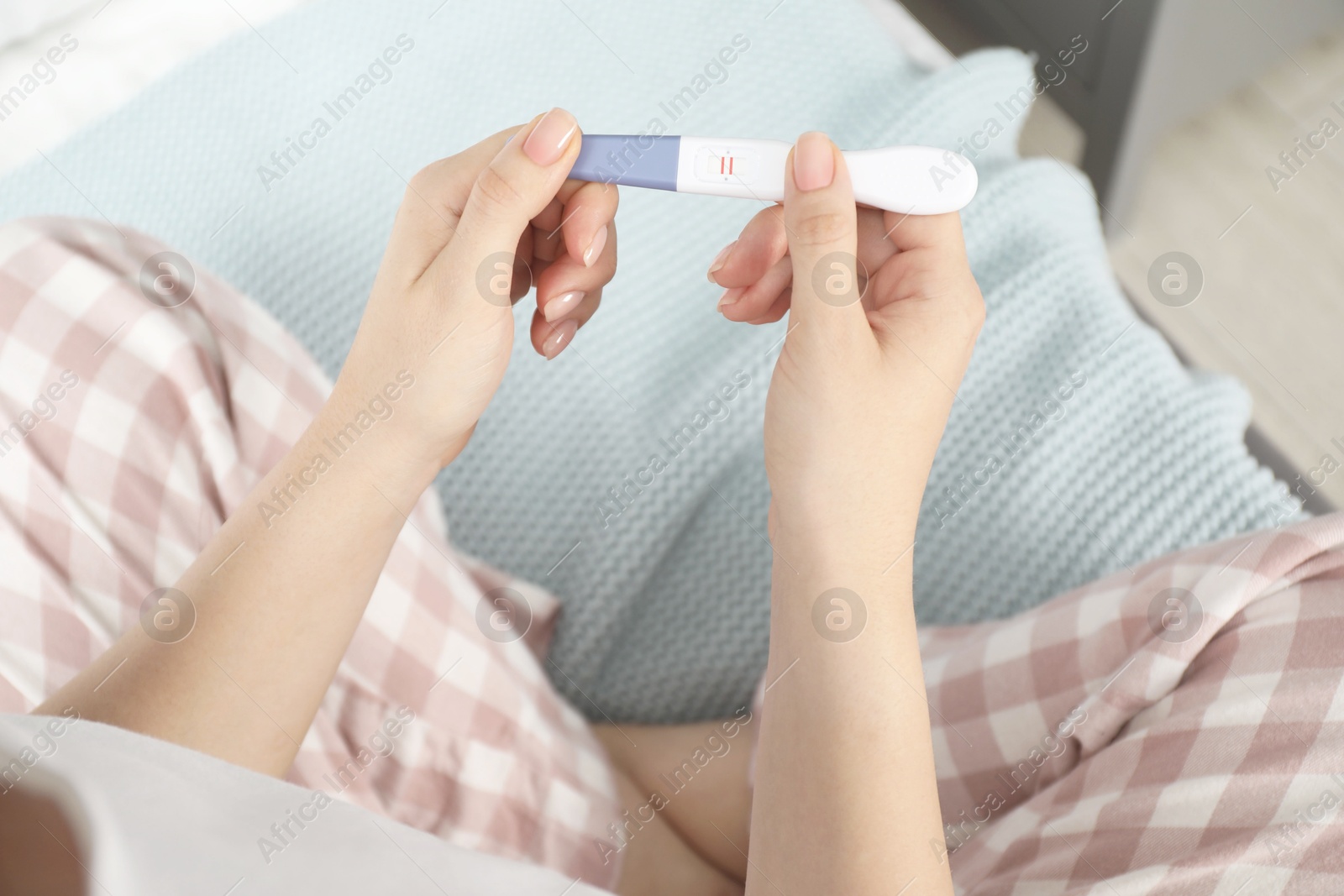 Photo of Woman holding positive pregnancy test indoors, closeup view