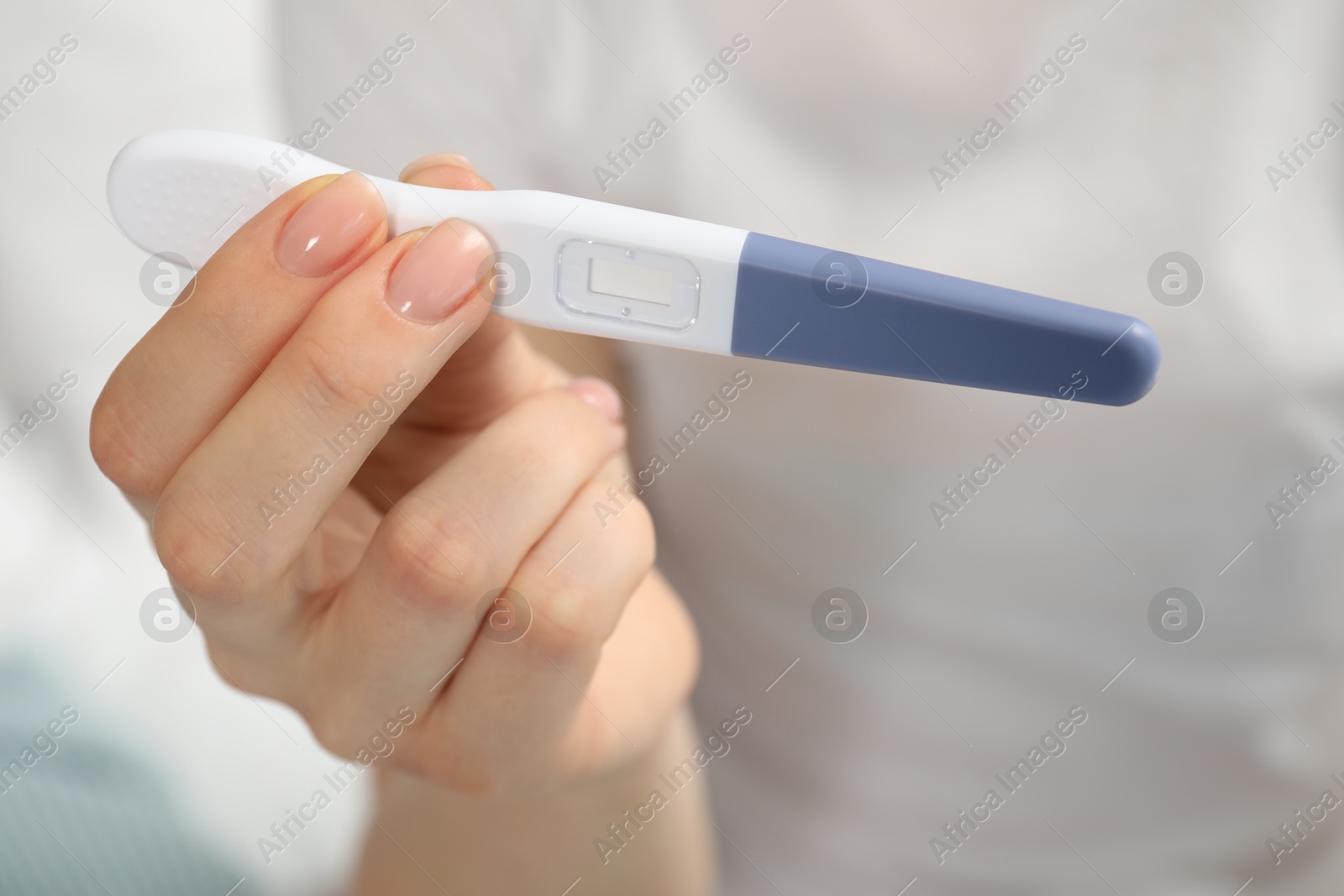 Photo of Woman holding pregnancy test indoors, closeup view