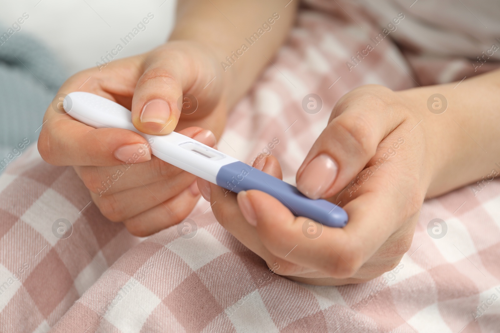 Photo of Woman holding pregnancy test indoors, closeup view