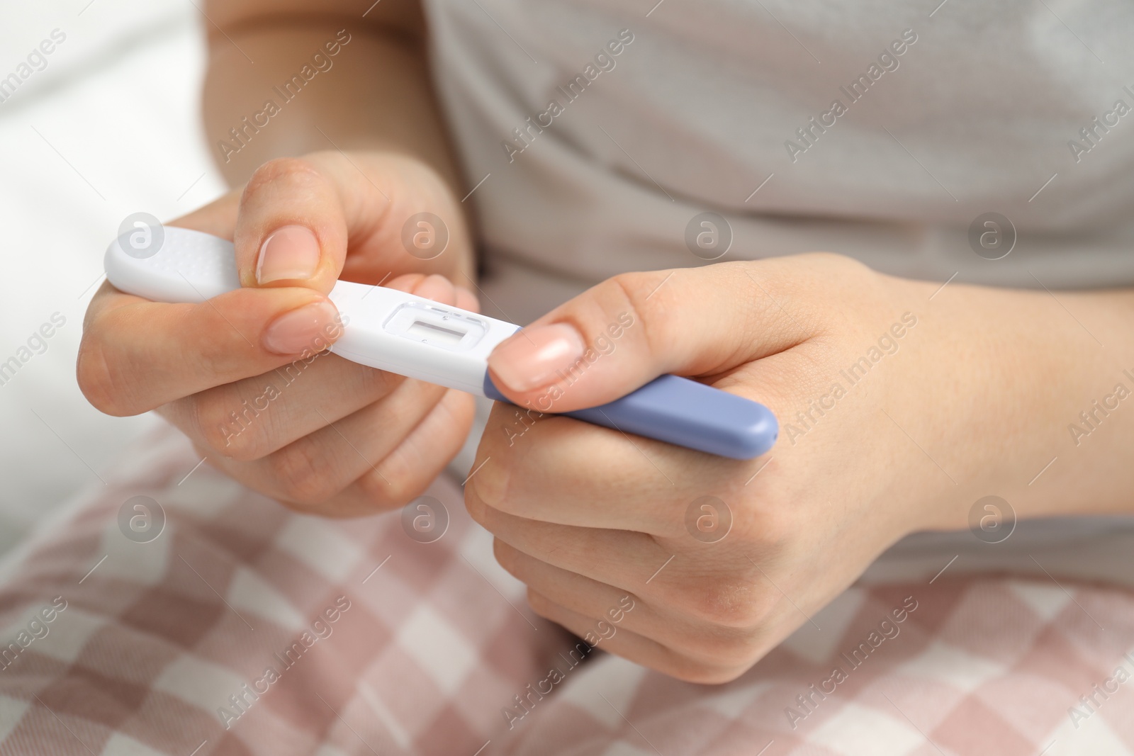 Photo of Woman holding pregnancy test indoors, closeup view