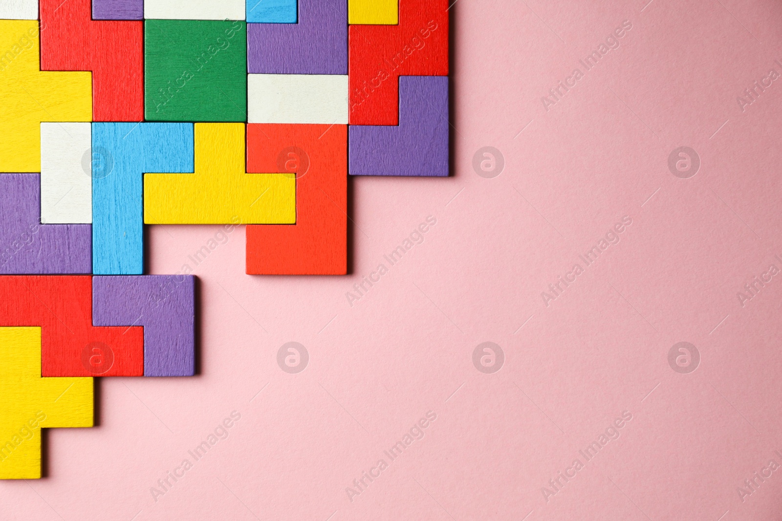 Photo of Colorful wooden puzzle pieces on pink background, top view. Space for text