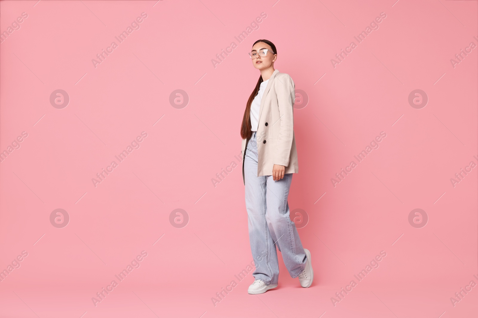 Photo of Stylish woman in beige jacket and jeans on pink background