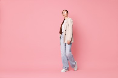 Photo of Stylish woman in beige jacket and jeans on pink background