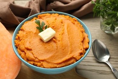 Photo of Tasty mashed sweet potato with butter and parsley in bowl served on wooden table, closeup