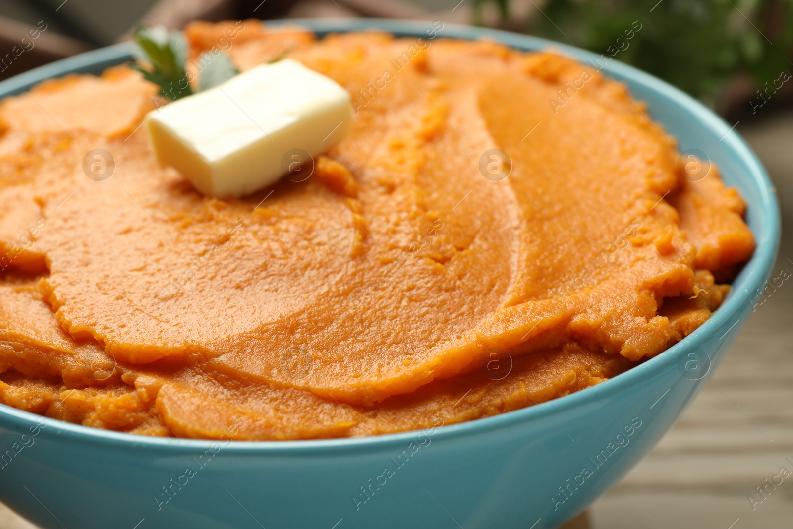 Photo of Tasty mashed sweet potato with butter in bowl on table, closeup