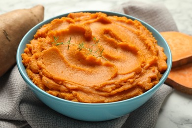 Photo of Tasty mashed sweet potato and thyme in bowl on table, closeup