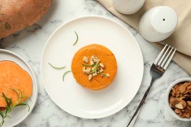 Photo of Tasty mashed sweet potato, rosemary and walnuts served on white marble table, flat lay