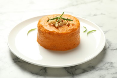 Photo of Plate with tasty mashed sweet potato, rosemary and walnuts on white marble table, closeup