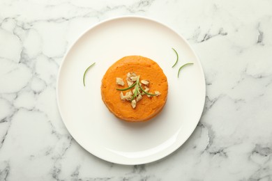 Photo of Plate with tasty mashed sweet potato, rosemary and walnuts on white marble table, top view